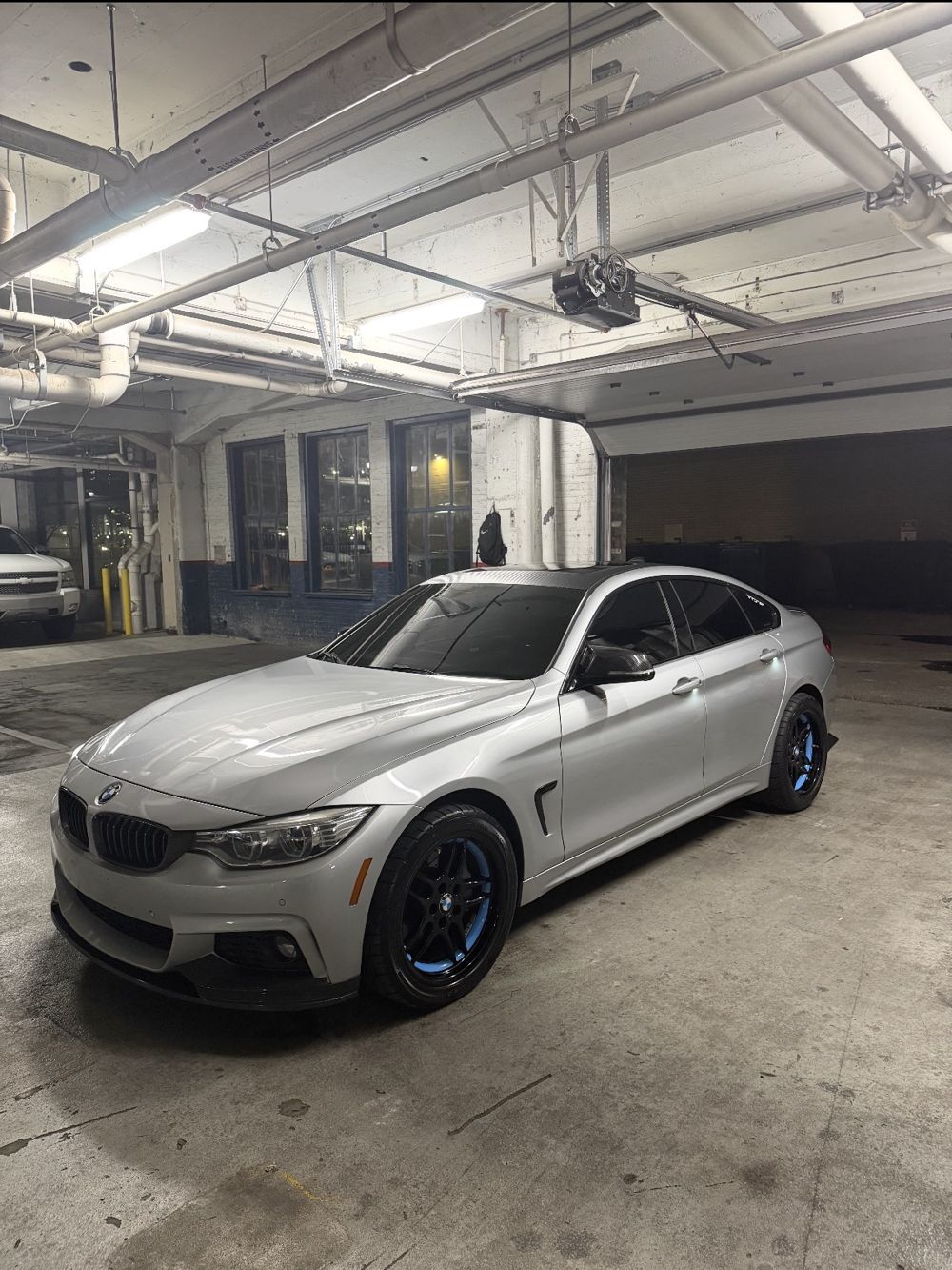 Silver BMW 4 Series Gran Coupe front three-quarter view in a garage after an exterior wash