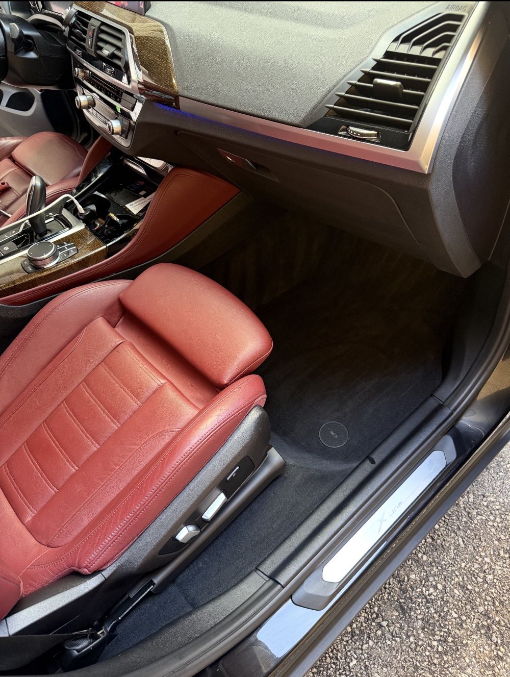 Same BMW X4 passenger side after detailing, clean carpet and conditioned red leather
