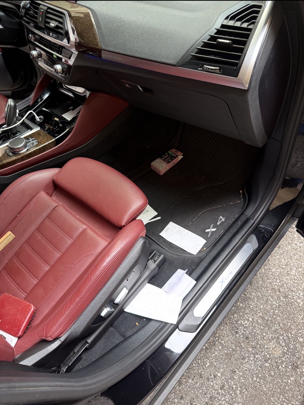BMW X4 passenger floor with papers and debris before detailing